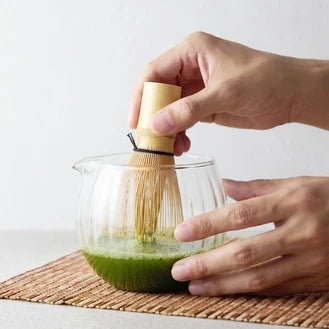 茶筅を使い、ガラスの器で挽き茶を水で点てる